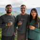 Three people wearing Nogales sweatshirts standing outdoors with mountains in the background.