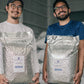Two men holding large bags of Gesha coffee beans in a warehouse setting.